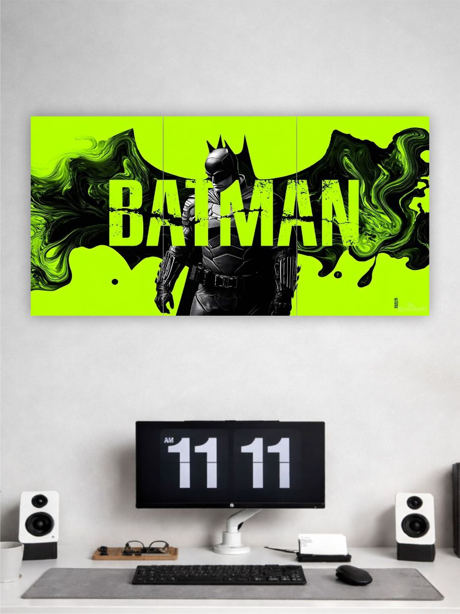 A three-panel canvas wall art set featuring Batman on a bright neon yellow background with green smoke effects, displayed on a light gray wall above a modern desk setup with a computer monitor, keyboard, speakers, and glasses.