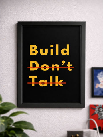 Framed poster with 'Build Don't Talk' text on a wall with decor elements.